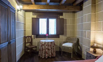 Rincón de la habitación con mesa y sillón
